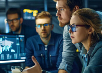 Team analyzing data visualizations on multiple monitors, representing the data from the top knowledge management software.